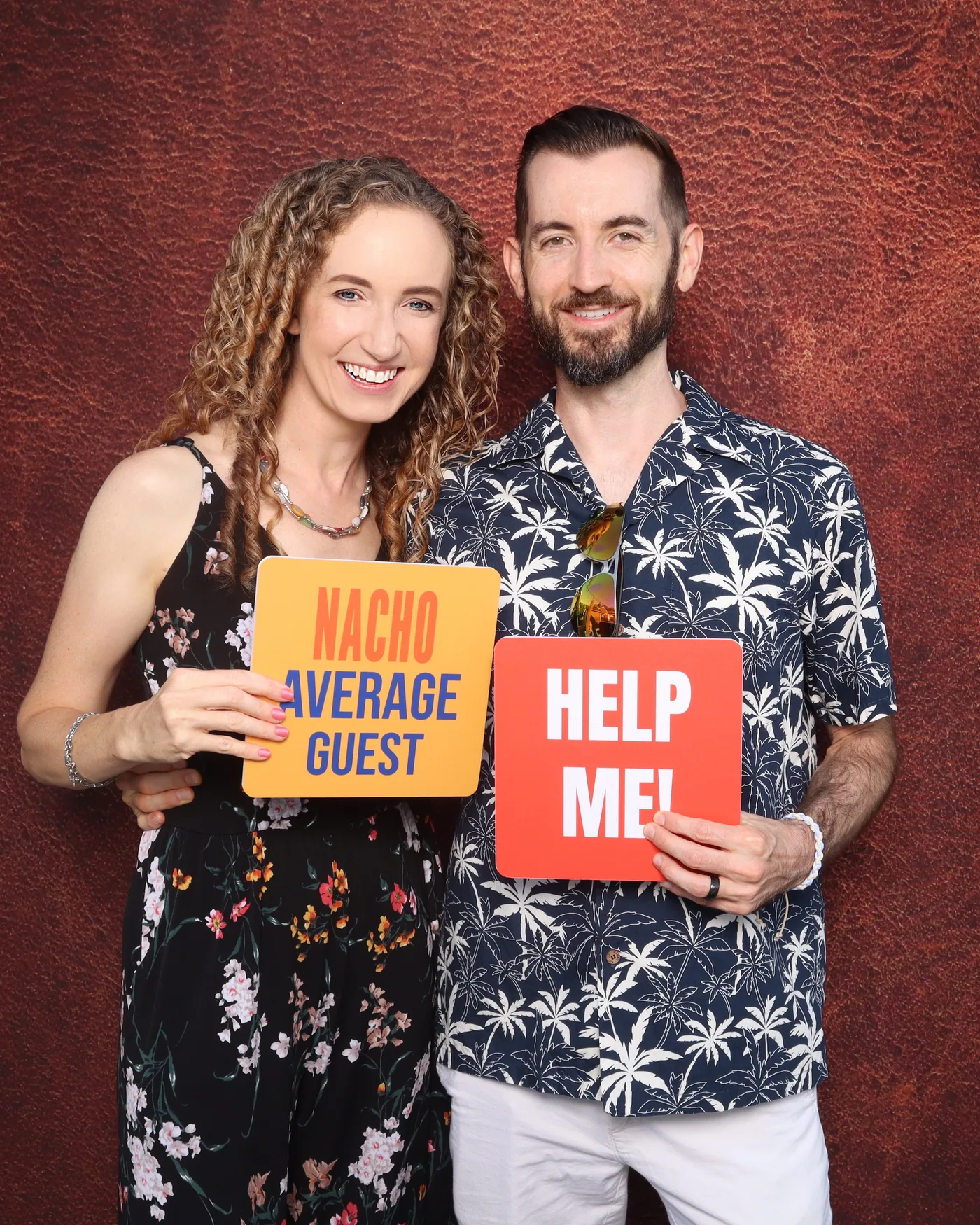 Couple holding "Nacho Average Guest" and "Help Me!" prop signs at a photo booth — Virginia Beach