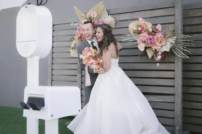 Wedding couple at outdoor floral backdrop photo booth